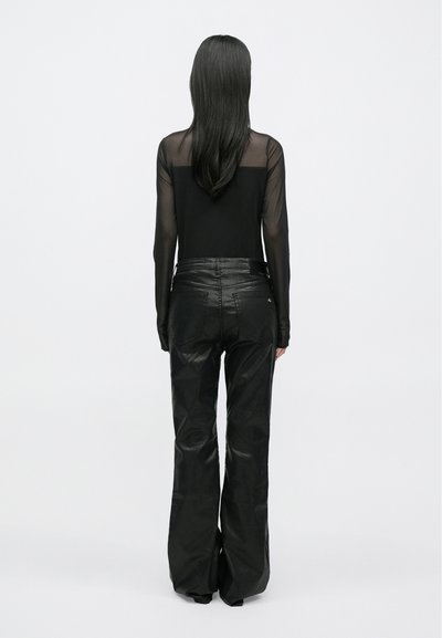 Čierny dlhý rukáv s priehľadnými zády a čierne rozšírené nohavice, oba z hladkých materiálov, vytvárajú elegantný, monochromatický vzhľad.