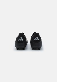 Black cleated soccer shoes featuring a textured mesh upper and rubber soles. Three diagonal stripes in gray on the heel.