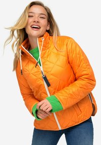 Giacca arancione trapuntata con colletto alto, zip bianca e polsini verde a coste. Design leggero con motivi a rombi visibili.