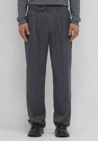 Pantalons gris ajustés avec un devant plat, des plis et une ceinture. Fabriqués en tissu texturé, ils possèdent une taille standard et des ourlets à revers.