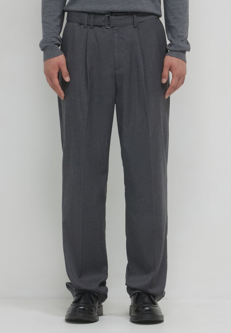 Pantalons gris ajustés avec un devant plat, des plis et une ceinture. Fabriqués en tissu texturé, ils possèdent une taille standard et des ourlets à revers.