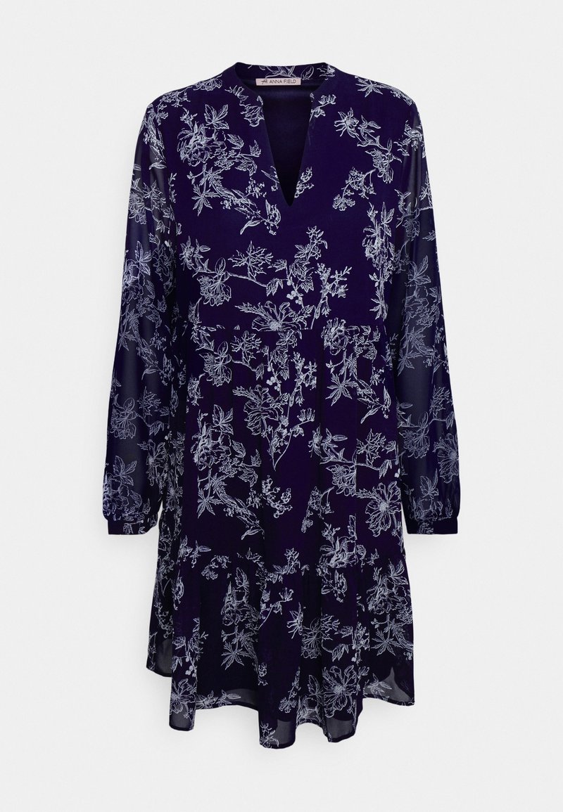 Robe bleu marine à manches longues avec imprimé floral blanc, encolure en V et ourlet légèrement évasé, réalisée en tissu léger et transparent.
