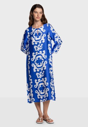 Blauwe lange jurk met witte draaipatronen, voorzien van een ronde halslijn en een keyhole-detail. Gemaakt van gladde stof, met lange mouwen en een vloeiend ontwerp.