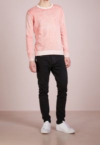 Melange pink knit sweatshirt with a crew neck, ribbed cuffs, and hem, paired with black slim jeans and white sneakers. Smooth texture.