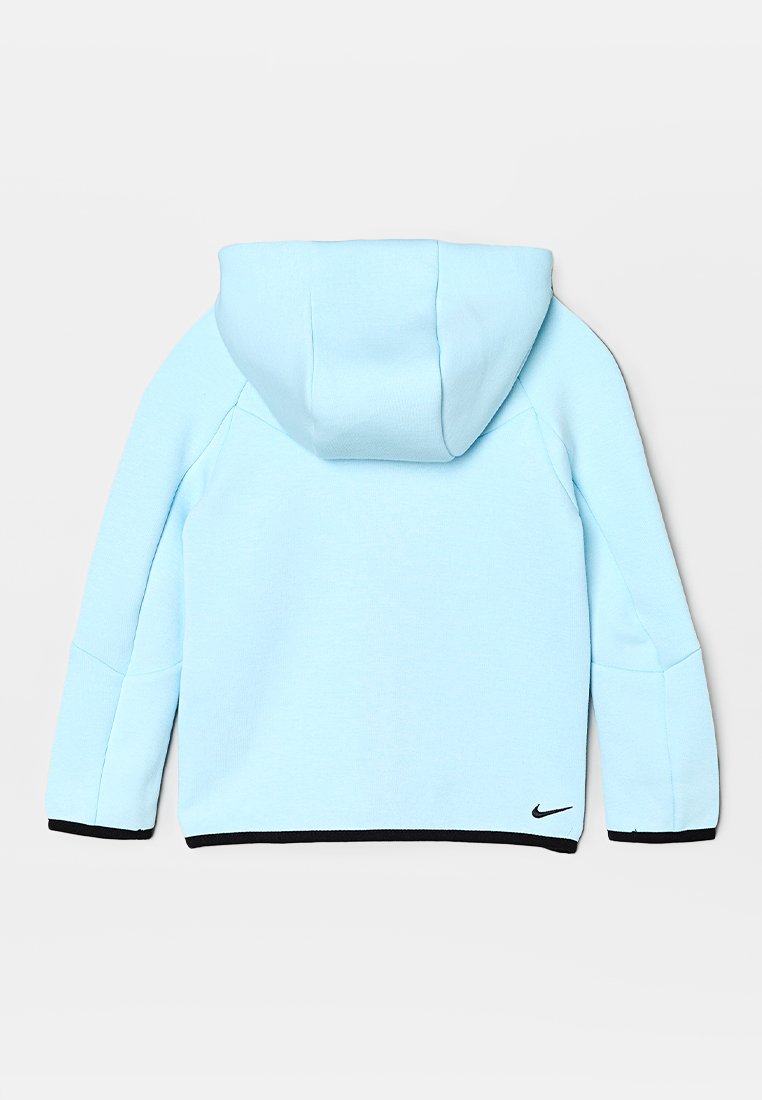 Haut de survêtement bleu clair avec une capuche proéminente, tissu texturé, bord noir aux poignets et à l'ourlet, et un petit logo Nike en bas à gauche.