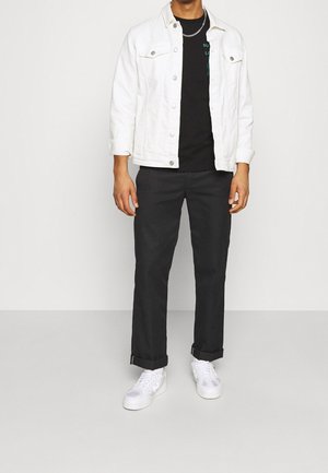 Valkoinen farkkutakki mustan T-paidan päällä, yhdistetty mustiin housuihin. Viimeistelty käärityillä hihansuilla ja valkoisilla lenkkareilla. Yksinkertainen, rento malli.