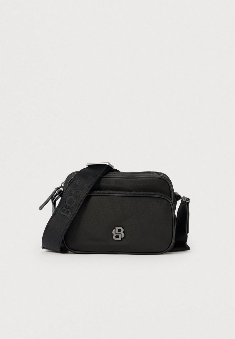 Borsa a tracolla rettangolare nera in materiale strutturato, con logo argento e tracolla regolabile con marchio. Chiusura a zip sulla parte superiore.