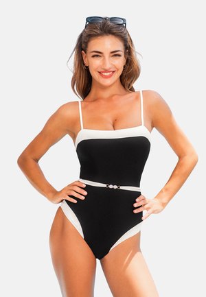 Traje de baño negro de una pieza con acentos blancos, que presenta tirantes finos, un escote cuadrado y un cinturón decorativo con tres detalles circulares.