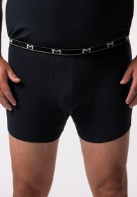 Černé boxerky s přiléhavým střihem, vyrobené z měkké látky, se značkovým elastickým pasem s bílým logem a detaily prošití.