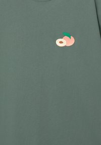 Grünes Baumwoll-T-Shirt mit gesticktem Design von zwei Pfirsichen und einem Blatt. Der Stoff ist glatt und hat einen klassischen Rundhalsausschnitt.