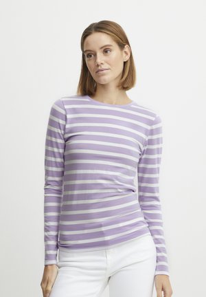 Chemise à manches longues rayée violette et blanche en tissu doux avec un col rond. Associée à un pantalon blanc, texture lisse.
