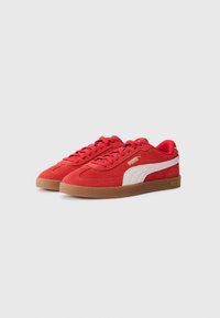 Røde ruskinds sneakers med hvid PUMA-logo, gummisål, flade snørebånd og et lavt profildesign. Har en kontrastfarvet gummisål.