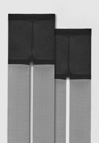 Dwie pary czarnych i szarych pończoch aż do ud położone płasko na białym tle, obok siebie.