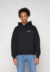 Black hoodie made of cotton blend, featuring a kangaroo pocket and drawstring hood. Accented with a white logo on the chest.