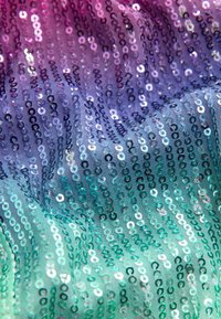 Sequin fabric featuring a gradient of colors from purple to teal, with shiny round sequins arranged in vertical rows. Smooth texture.