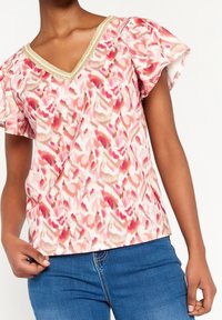 Kratší rukáv s výstřihem do V, s růžovým květinovým vzorem a zlatými detaily kolem výstřihu, vyrobeno z lehkého materiálu.