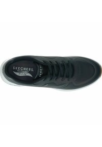 Zapato Skechers negro con parte superior sintética lisa, detalles de malla, cordones texturizados y suela blanca con acentos de goma. Incluye plantilla ArchFit.