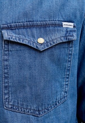 Blauwe denim blousezak met klep en enkele metalen drukknop, voorzien van een klein wit label met de tekst "JACK&JONES".