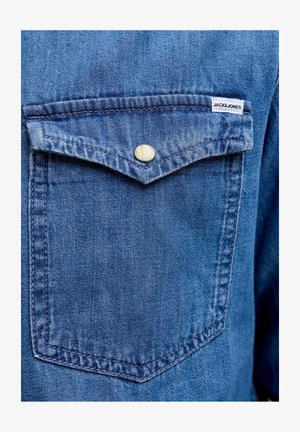 Blauwe denim blousezak met klep en enkele metalen drukknop, voorzien van een klein wit label met de tekst "JACK&JONES".