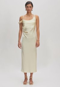 Satin-Midi-Kleid in zartem Creme mit quadratischem Ausschnitt und einem schmalen Trageriemen. Hat einen Seitenschlitz und ein minimalistisches Design.