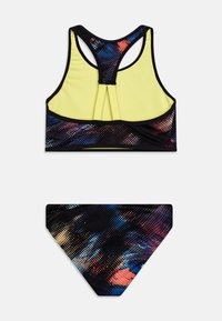 Twee-delige zwemoutfit met een gele racerback top met zwart en kleurrijke spetterpatronen, en een bijpassende zwarte bikini broek met accenten.