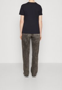 Marineblå bomulds t-shirt med korte ærmer, parret med grå, løstsiddende, blege jeans med baglommer og synlige syninger.