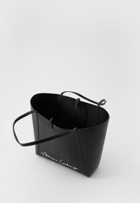 Borsa tote nera in ecopelle con due manici, apertura superiore, design angolare, con logo bianco "Armani Exchange" sul fronte.