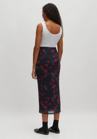 Wit tanktop; bloemen midi rok in marineblauw met rode rozen; slanke pasvorm, gladde textuur; gecombineerd met zwarte ballerina's en sokken.