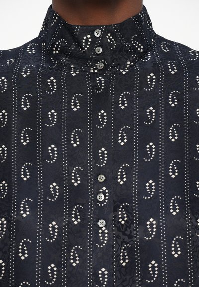 Zwarte blouse met patroon, voorzien van een hoge kraag, knoopsluiting aan de voorkant en witte decoratieve accenten in een paisleydesign. Soepele stofstructuur.
