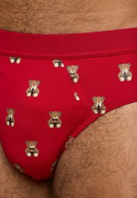 Røde bomuldsunderbukser med et gentaget bjørnedesign i forskellige poser, udstyret med en blød elastisk talje og en glat tekstur.