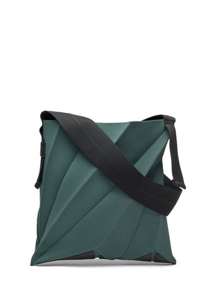 Sac bandoulière vert avec des plis géométriques et une large sangle d'épaule noire réglable sur fond blanc.