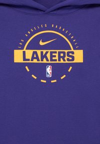 Lilla hættetrøje med gul "LAKERS" print, "Los Angeles Basketball" tekst ovenfor og et Nike logo. Inkluderer NBA insignia nederst.