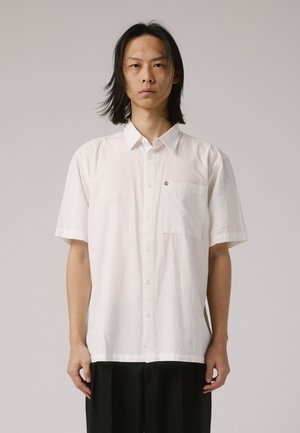 Chemise blanche à manches courtes avec un col boutonné, tissu texturé, poche sur le devant et détail de logo petit sur la poitrine.