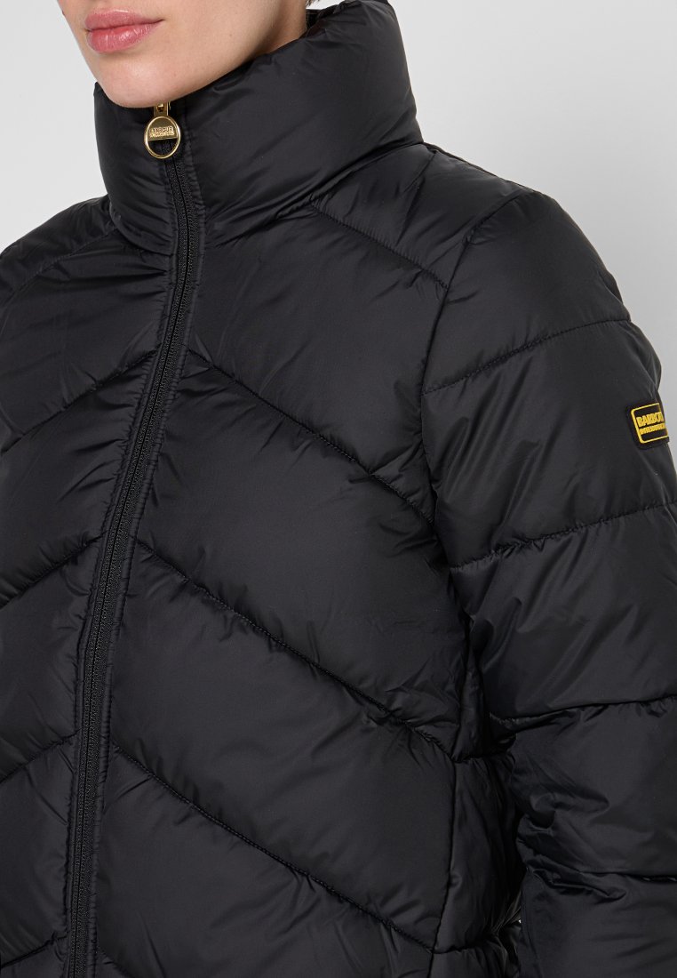 Schwarze Steppjacke mit hohem Kragen, steppmuster und goldenen Reißverschlussdetails. Verfügt über ein kleines Logo auf der linken Schulter.