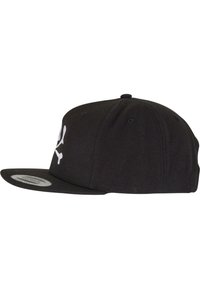 Musta snapback-lippis tasaisella rimalla, jossa on valkoinen pääkallo ja ristiluutukuvasto etupuolella. Valmistettu tekstuurikankaasta.