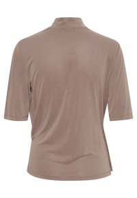 Kortärmad topp i ljusbrunt tyg med en subtil glans. Har en falsk krage och rundad nederkant med sidospår för ökad rörelsefrihet.
