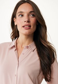 Lichtroze blouse met een kraaglijn, knoopdetails en een zachte stofstructuur. Lange mouwen en een relaxte pasvorm.
