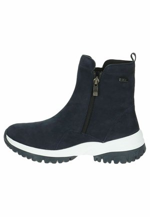 Botte chelsea en suede bleu marine avec fermeture éclair sur le côté et tirette, featuring une semelle intermédiaire blanche et une semelle extérieure en caoutchouc noir texturé pour une meilleure adhérence.