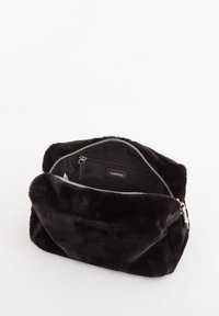 Zwarte cosmetische tas van nep bont met ritssluiting en binnenzak. Zachte textuur, rechthoekige vorm en een gebrandmerkt etiket aan de binnenkant.