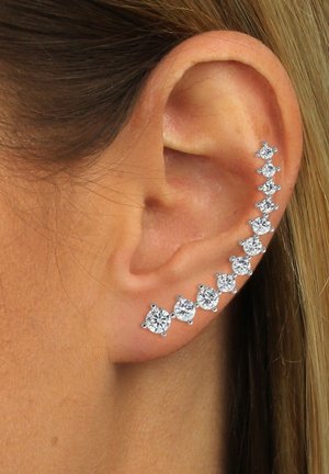 Silver ear cuff featuring a gradient of round, clear gemstones arranged in ascending order from small to large along the edge of the ear.