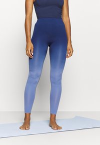 Höga leggings i en gradient från marinblå till ljusblå, med en mjuk, elastisk textur. Designen har inga synliga sömmar.