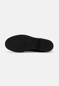 Black rubber shoe sole with textured grip pattern and brand logo. Flat design with rounded edges, suitable for various footwear styles.