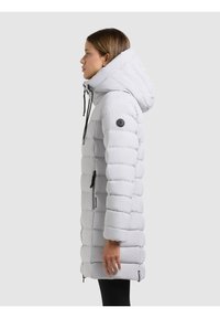 Ljusgrå vadderad jacka med huva, med quiltade sektioner, en svart logotyp på ärmen och två fickor med dragkedja.