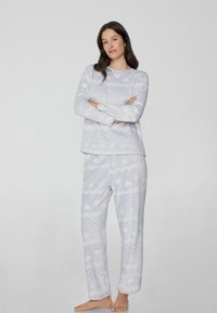 Himmelblaues Pyjama-Set mit einem Langarmoberteil mit Herzmustern und passenden Hosen mit Zickzackdesigns, hergestellt aus weichem, kuscheligem Material.