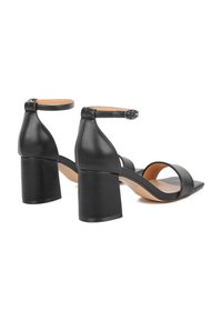 Sandali neri in pelle con tacco alto, cinturino alla caviglia, tacco largo e due cinturini frontali. Texture liscia e design minimalista.