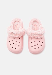 Roosa sussid, millel on ümmargused ventilatsiooniaugud ja pehme, kasukas äär aukude ümber sooja ja mugavuse tagamiseks.