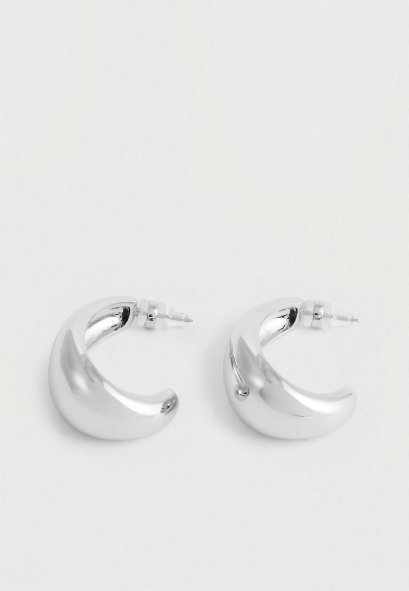 Para błyszczących, masywnych srebrnych kolczyków w kształcie półksiężyca z zapięciem na wcisk na białym tle.