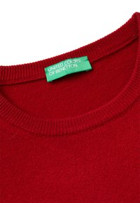 Roter Strickpullover-Ausschnitt mit einem grünen Etikett, auf dem "United Colors of Benetton" im Kragen genäht ist.