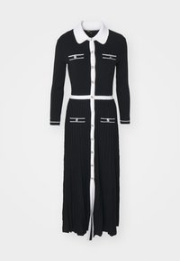 Robe tricotée noire avec un col blanc et des boutons, dotée de rayures horizontales sur les poches, d'un haut ajusté et d'une jupe plissée.