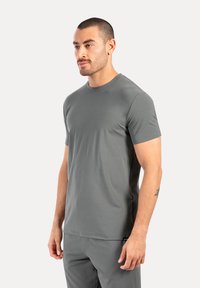 Camiseta gris de manga corta, hecha de una tela suave y ligera, con un escote redondeado y un diseño ajustado, combinada con pantalones a juego.